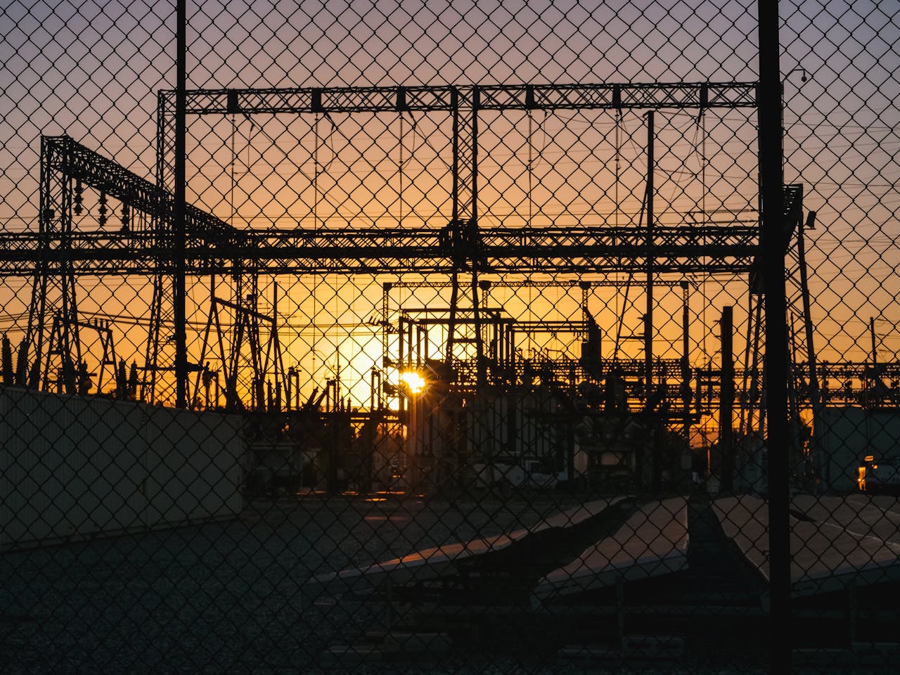 Silhouette of industrial power lines during sunset, symbolizing renewable energy.