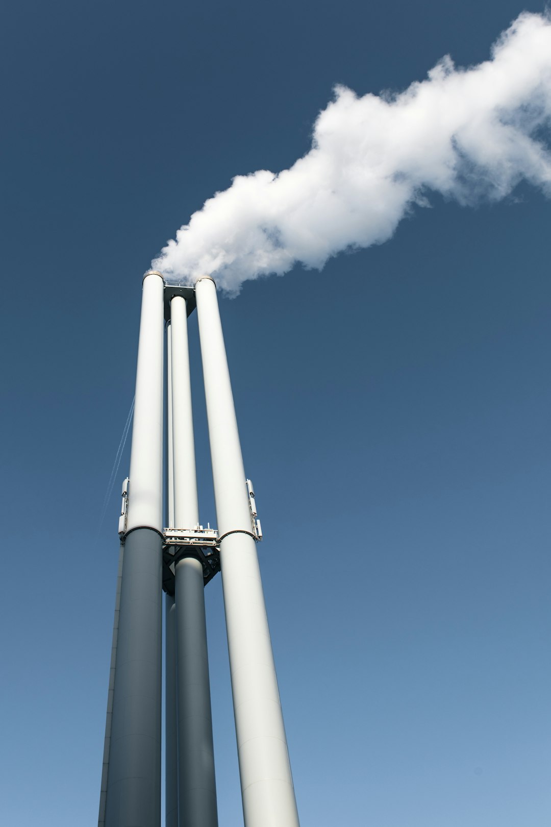 three-smokestacks-emitting-white-smoke-against-blue-sky-yzmw0tl3pfa